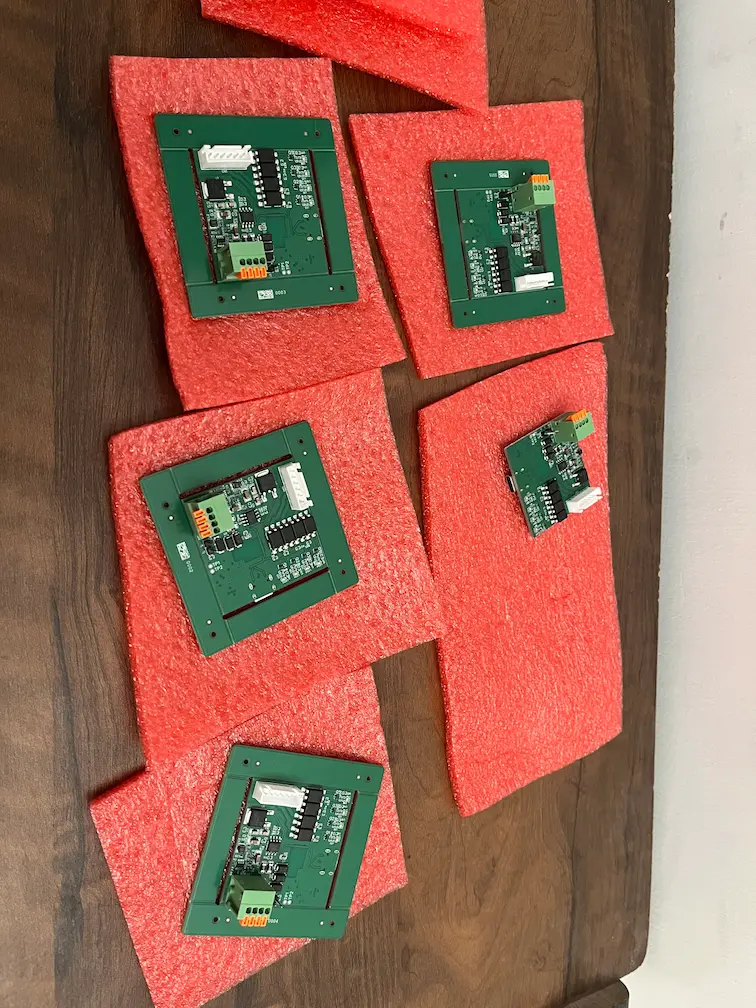 Top-down view of five assembled curtain controller boards with sequential serial numbers laid out on anti-static foam