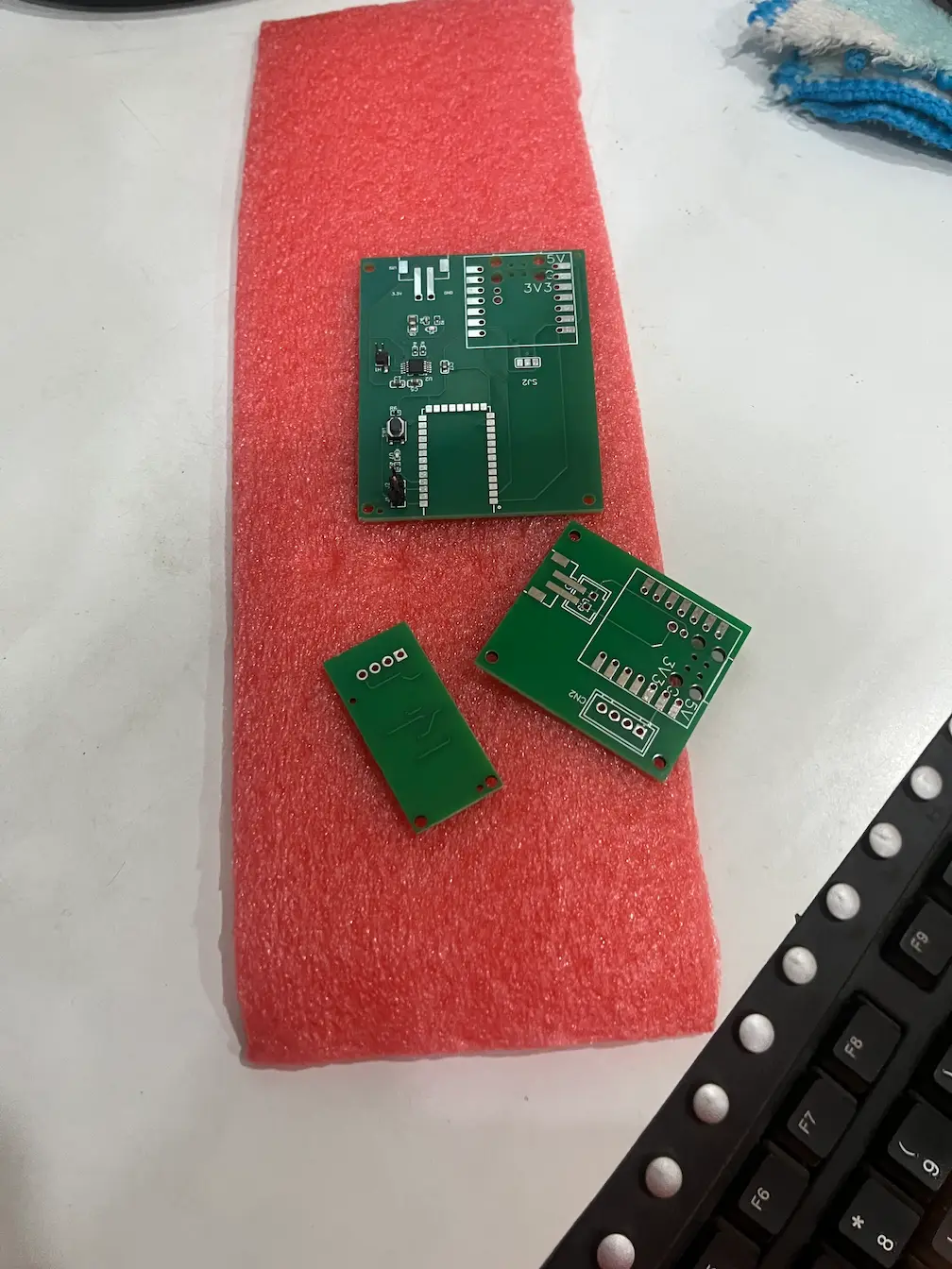 Four separate bare custom PCBs fabricated by JLCPCB laid out on protective foam