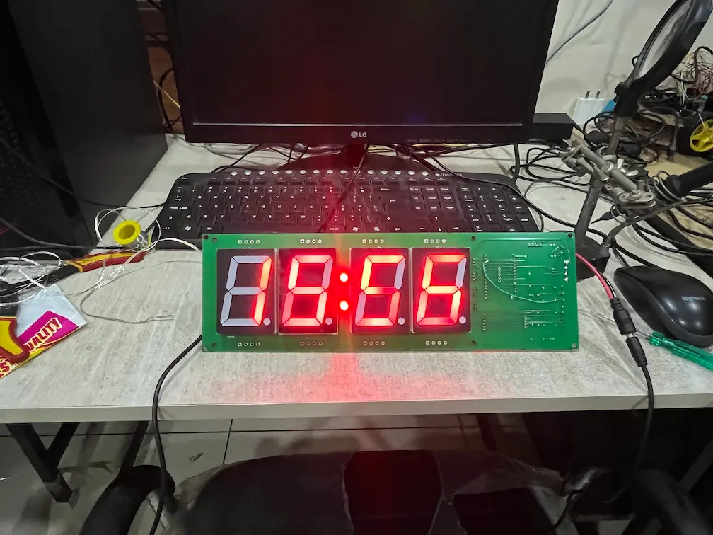 Assembled hoop alarm clock board powered on a workbench, showing the time on four large red 7-segment digits