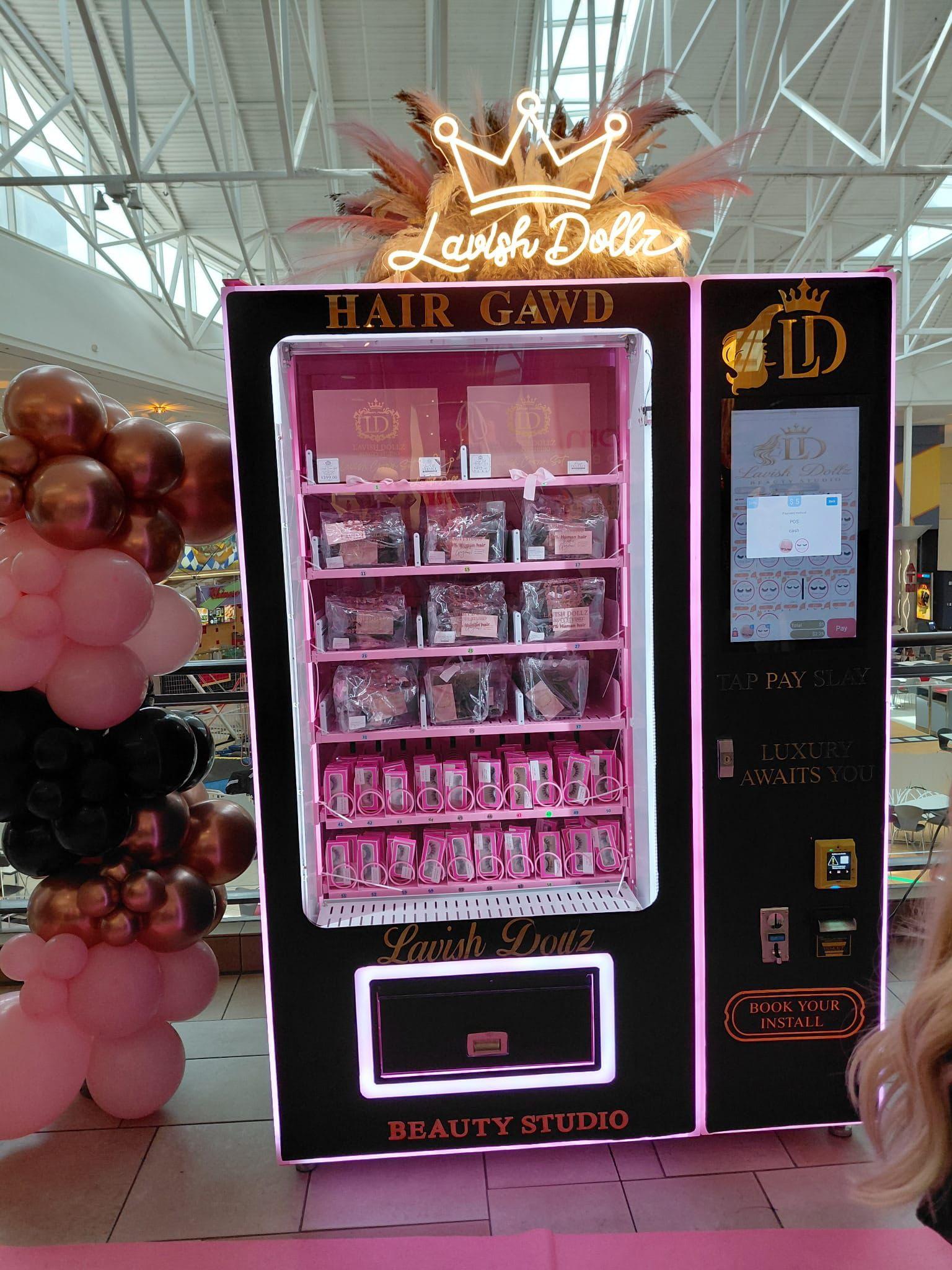 Lavish Dollz vending machine launch at Moore, Oklahoma mall location — pink and gold beauty product vending machine dispensing hair extensions and eyelashes